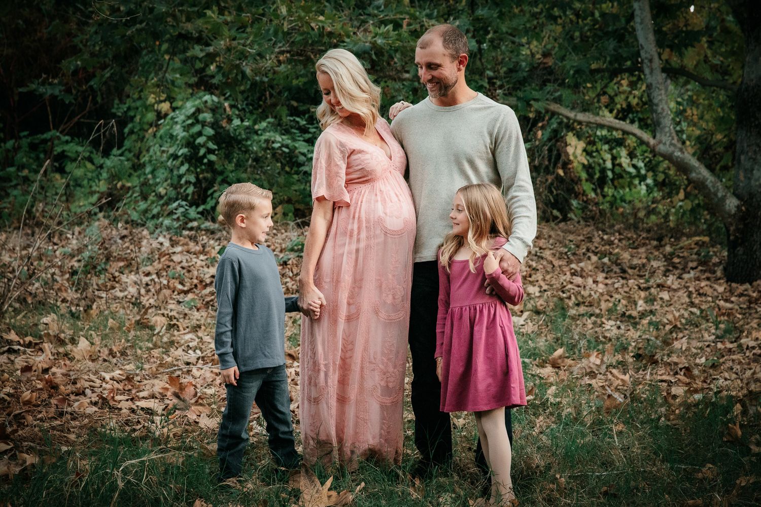 Pregnant woman in pink dress with husband and two children in autumn forest family photo. in Bonsall, near Fallbrook, & Temecula
