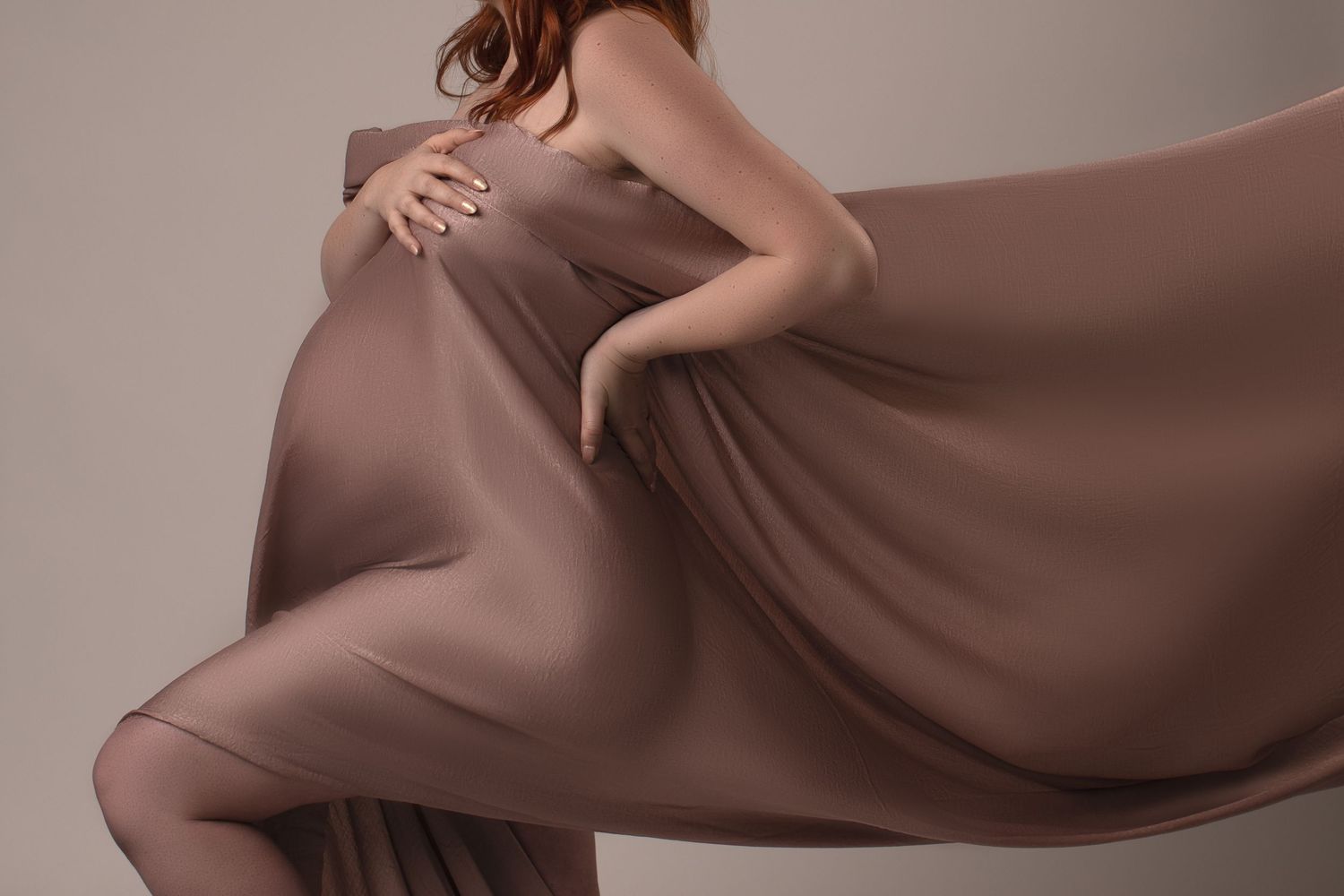 Close-up of pregnant woman wrapped in flowing taupe chiffon fabric for an artistic maternity portrait. Bonsall, near Fallbrook, & Temecula