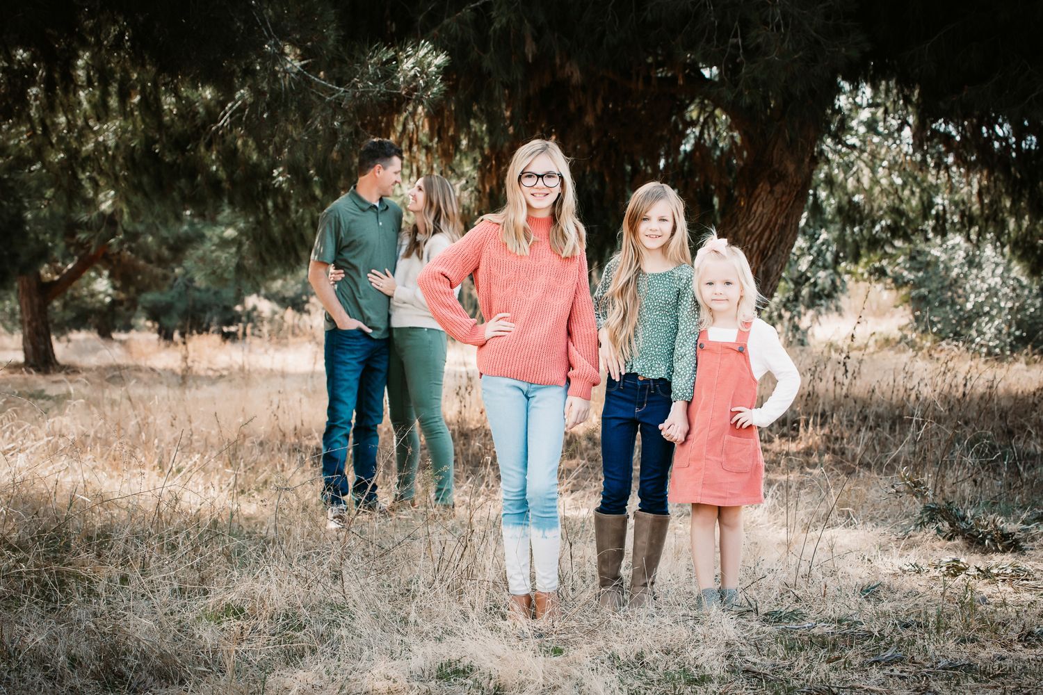 Mother and three children stand in a dry field beneath a large tree in natural light in Fallbrook