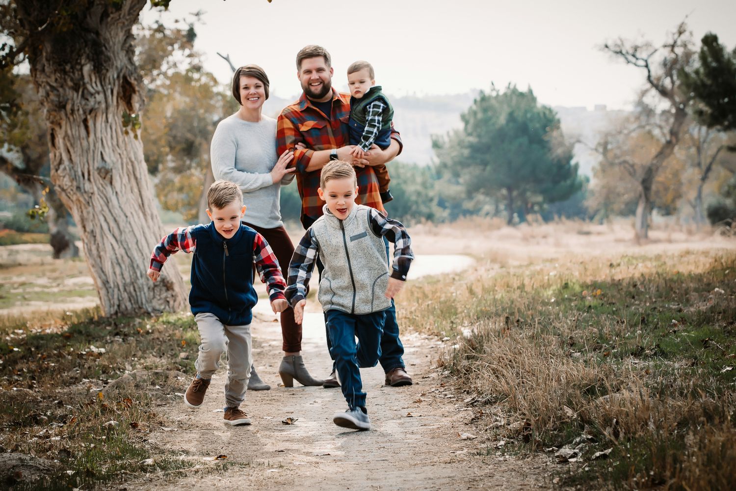 Family of five with kids running down a sunny outdoor trail.