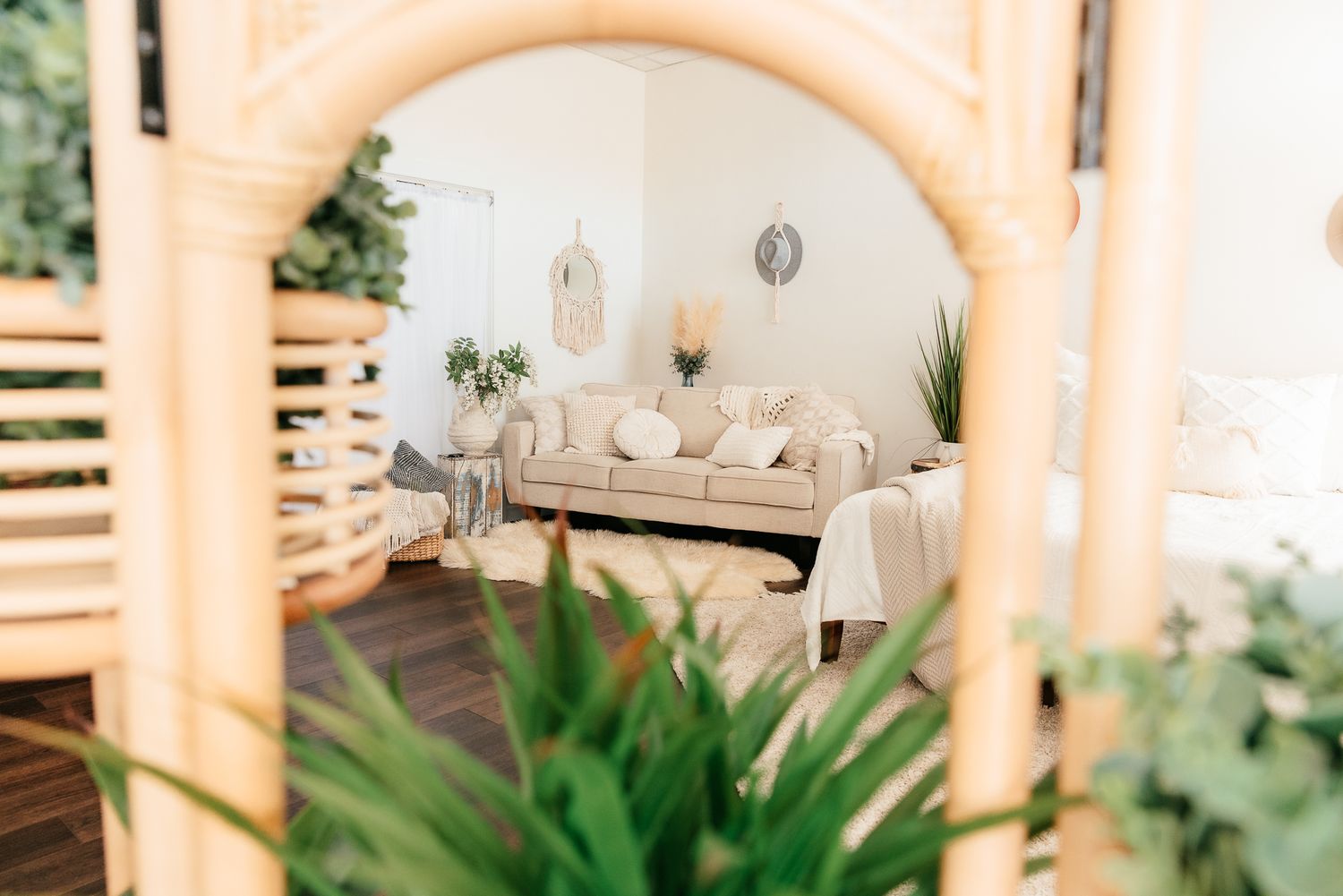 Boho photography studio reflected in rattan mirror with neutral sofa, plants, and white decor. in the Bonsall Studio near Fallbrook, Vista,