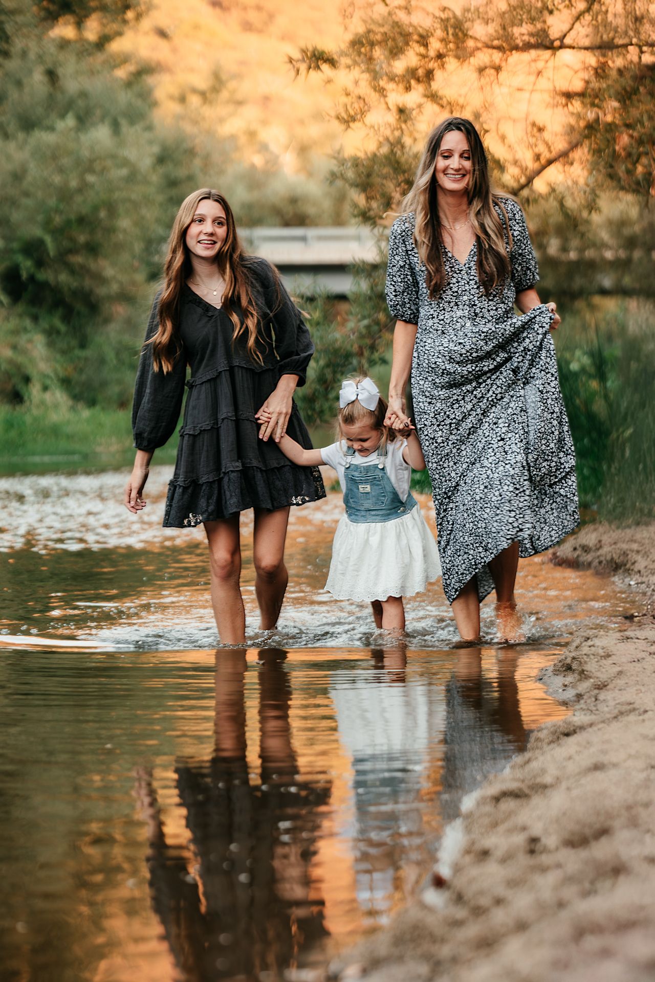 Two women and toddler girl walking through shallow water at golden hour by river in Bonsall, near Fallbrook, & Temecula