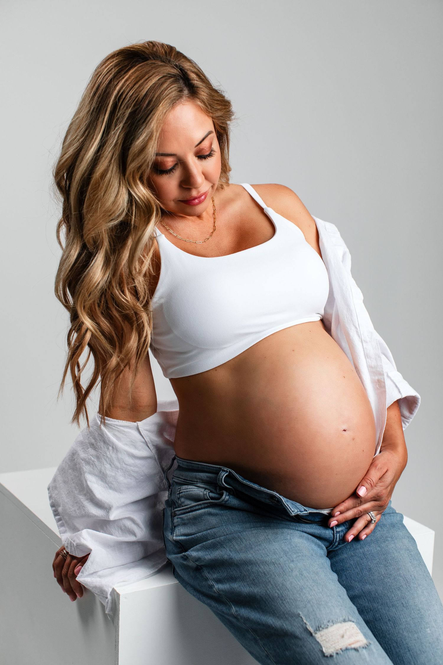 Maternity Session in Studio with white seamless background with jeans and white top and bare belly in Bonsall, near Vista and Fallbrook