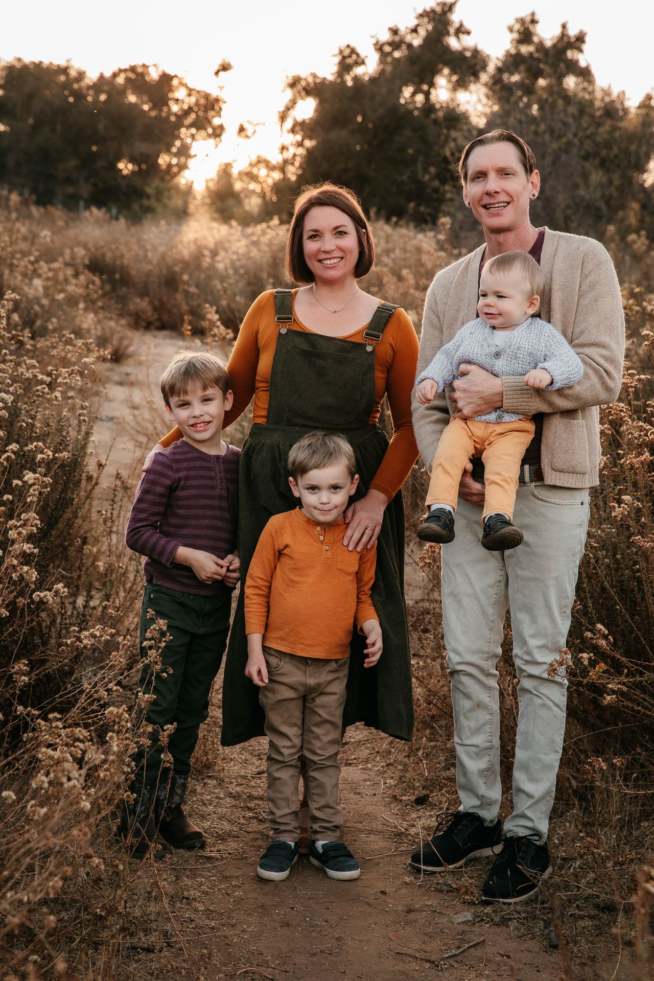 Family of five posing at sunset on a wildflower-lined trail.
