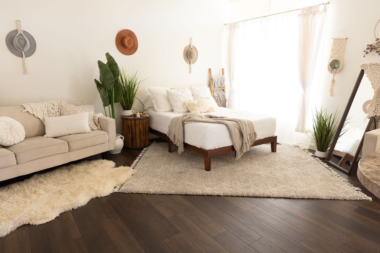 Bright boho-style photography studio with white bed, neutral rug, plants, and macrame wall decor. in the Bonsall Studio near Temecula
