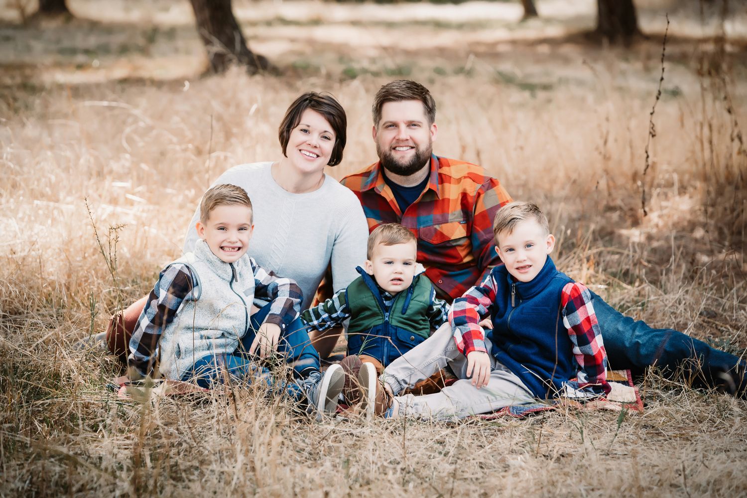 Family of five with three young boys sitting in dry grass field for fall portrait.  In Bonsall, near Oceanside