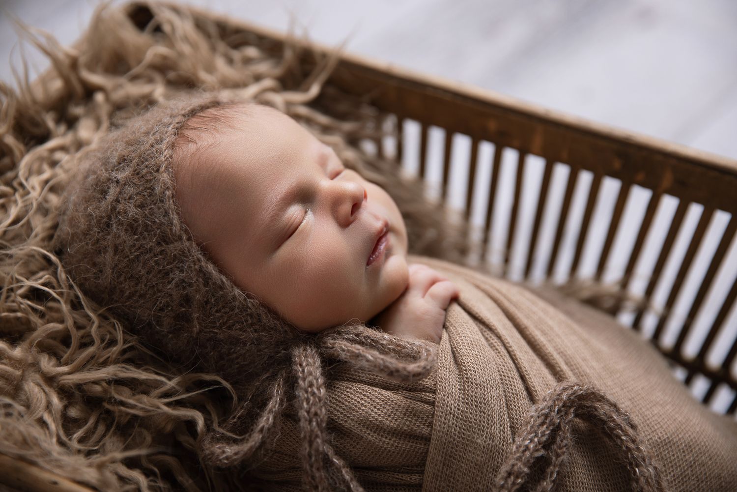 Valley Center Newborn baby session. baby sleeping in brown knit bonnet and wrap inside rustic wooden crate with fur.