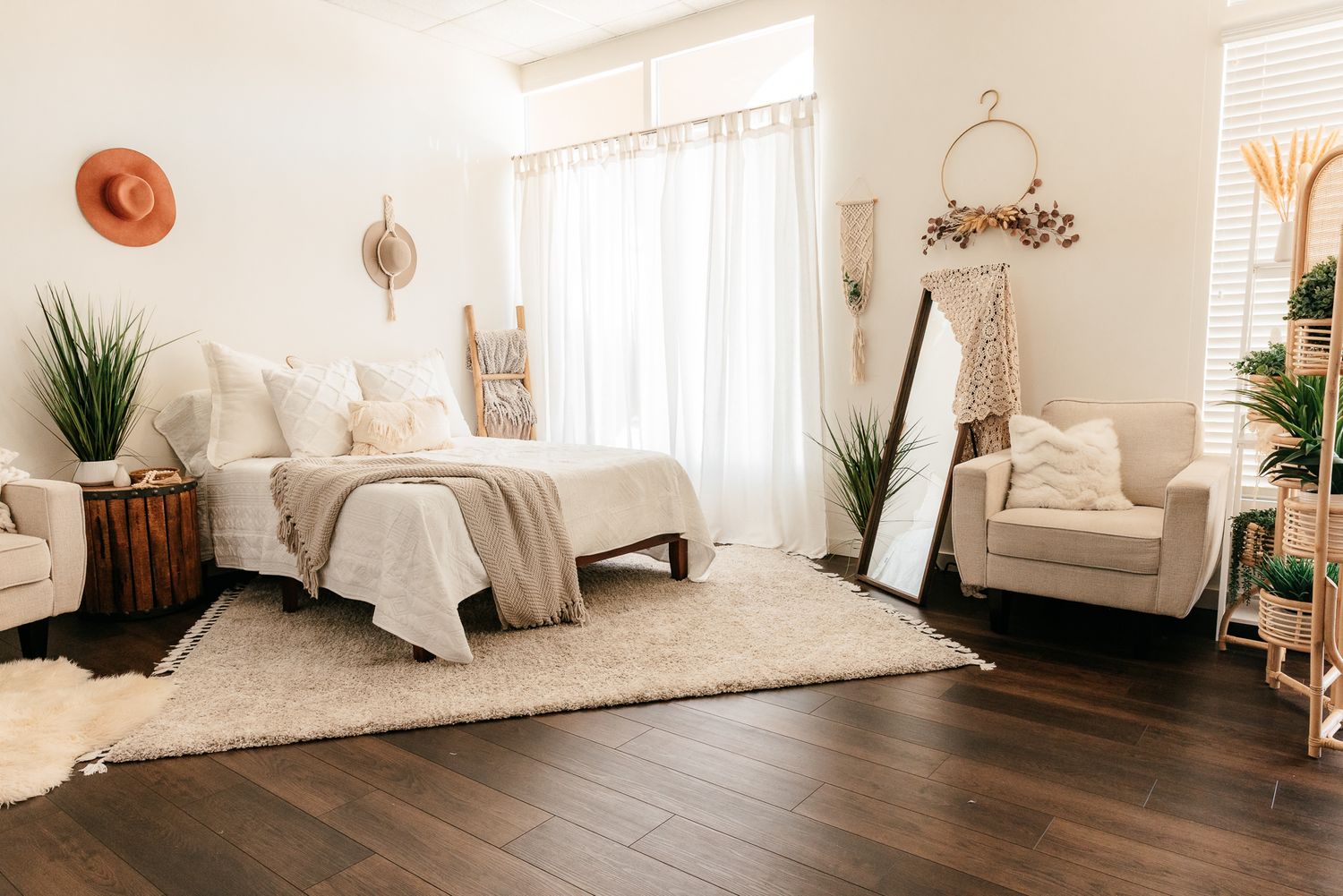 Bright boho bedroom featuring a white bed, shag rug, macrame decor, mirror, and sheer curtains. in the Bonsall Studio near Fallbrook, Vista,