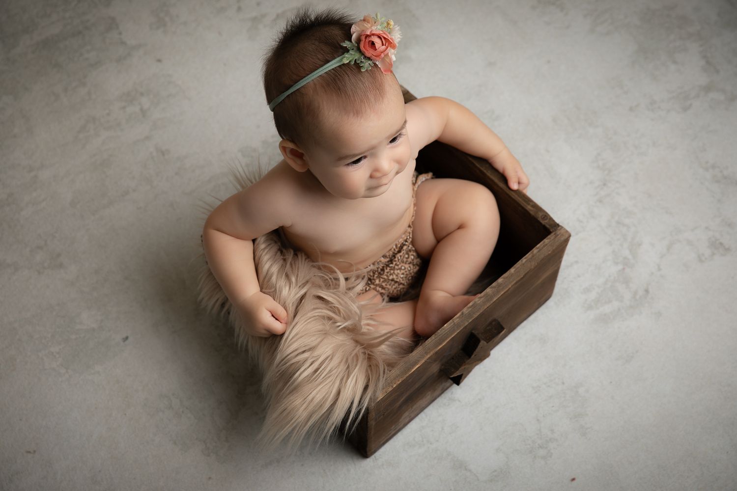 Baby girl with floral headband sitting in rustic wooden crate. Vista Newborn Photographer