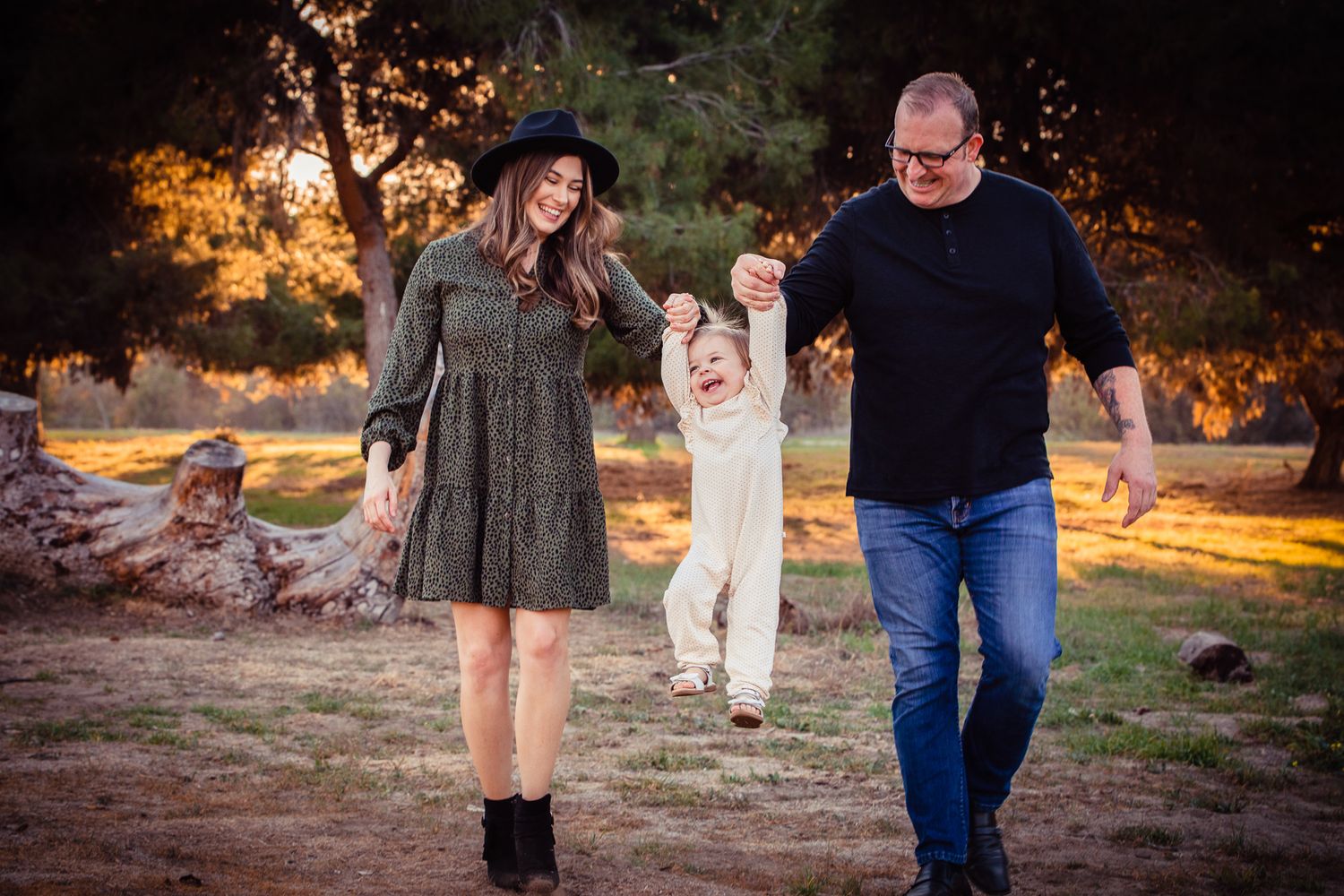 Young family swinging toddler between parents during golden hour outdoor photo session at the Bonsall Preserve.