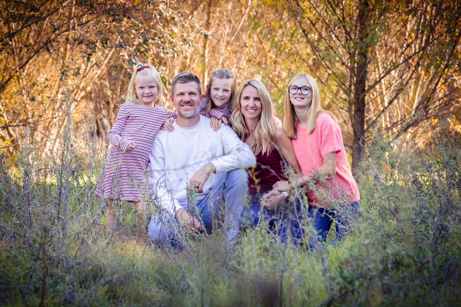 Smiling family of five poses together among colorful fall shrubs in an outdoor setting. in Bonsall near Fallbrook