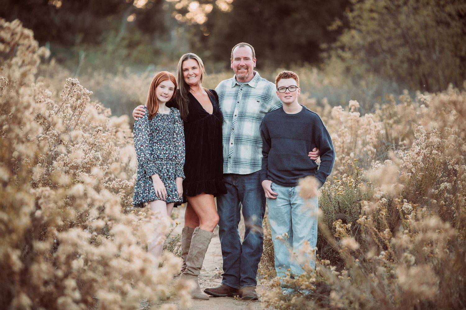 Family of four smiling outdoors among wildflowers during golden hour in Bonsall CA