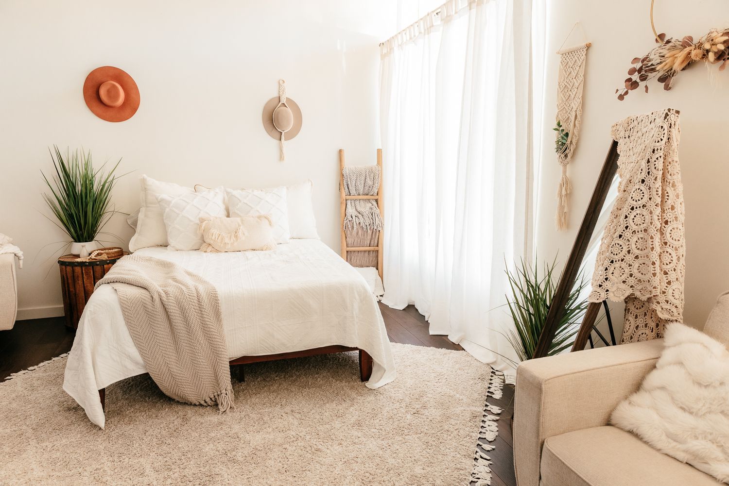 Bright boho photography studio with white bed, sheer curtains, ladder decor, and potted plants in the Bonsall Studio near Temecula