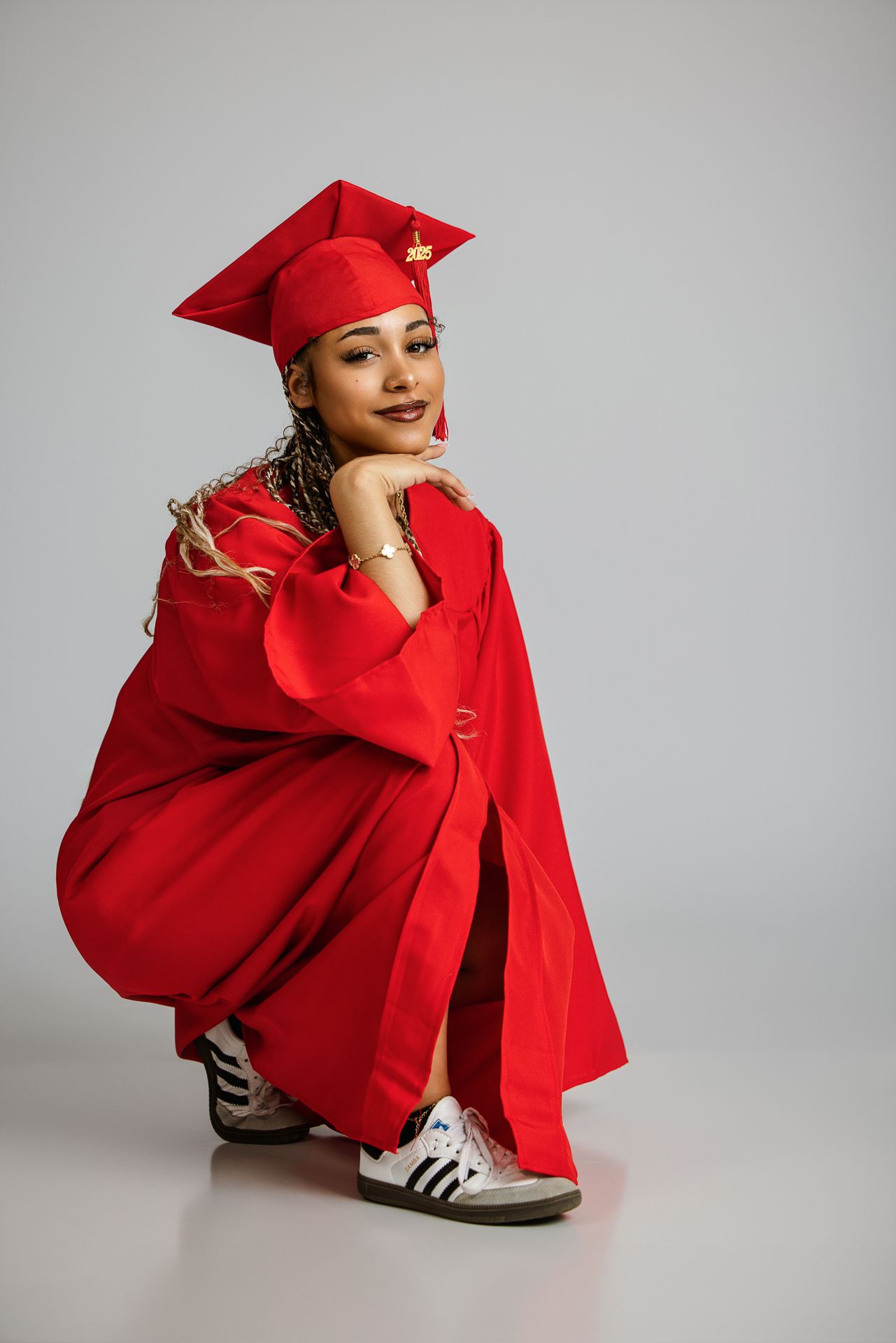 Graduates in red cap and gown, wearing white sneakers for a 2025 graduation photo. Senior photography session in studio in Bonsall