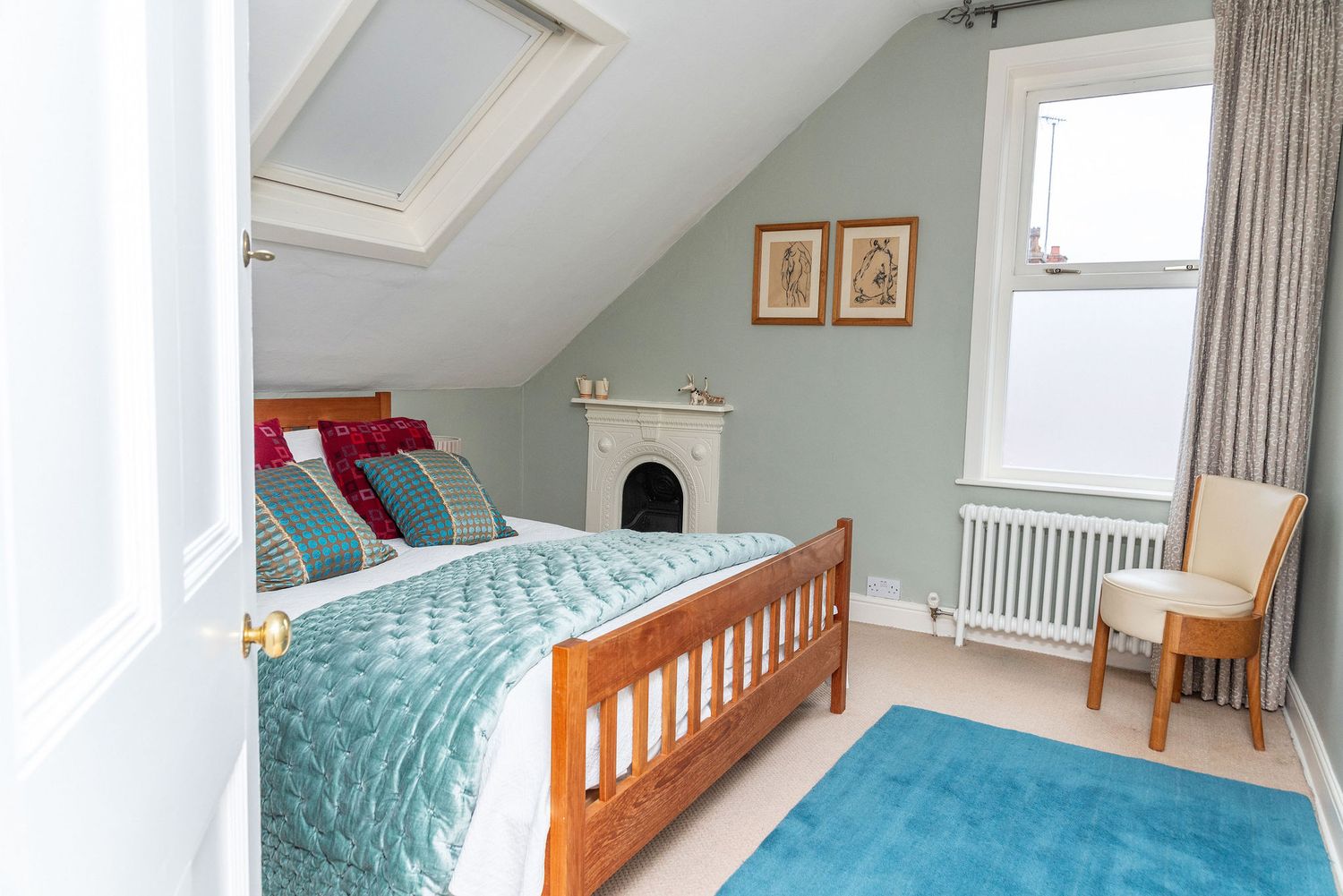 A bright and airy bedroom with turquoise accents features wooden furniture and natural light streaming through windows.