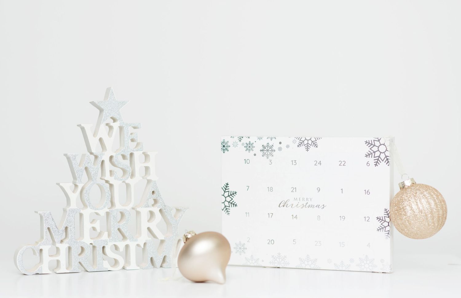 White Christmas tree decoration with card and ornament on light background.