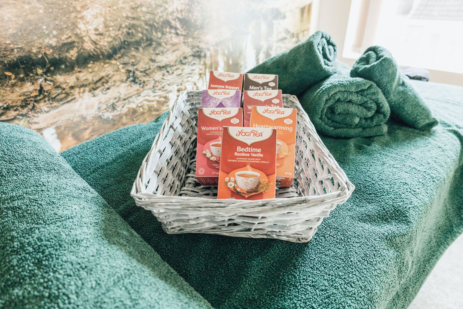 A wicker basket containing tea packets and green towels for spa treatments.