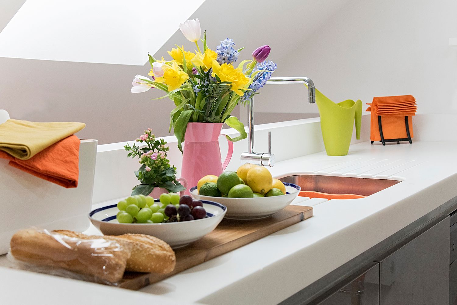 Fresh spring rolls with fruit and flowers arranged on a wooden cutting board with colourful dipping bowls.