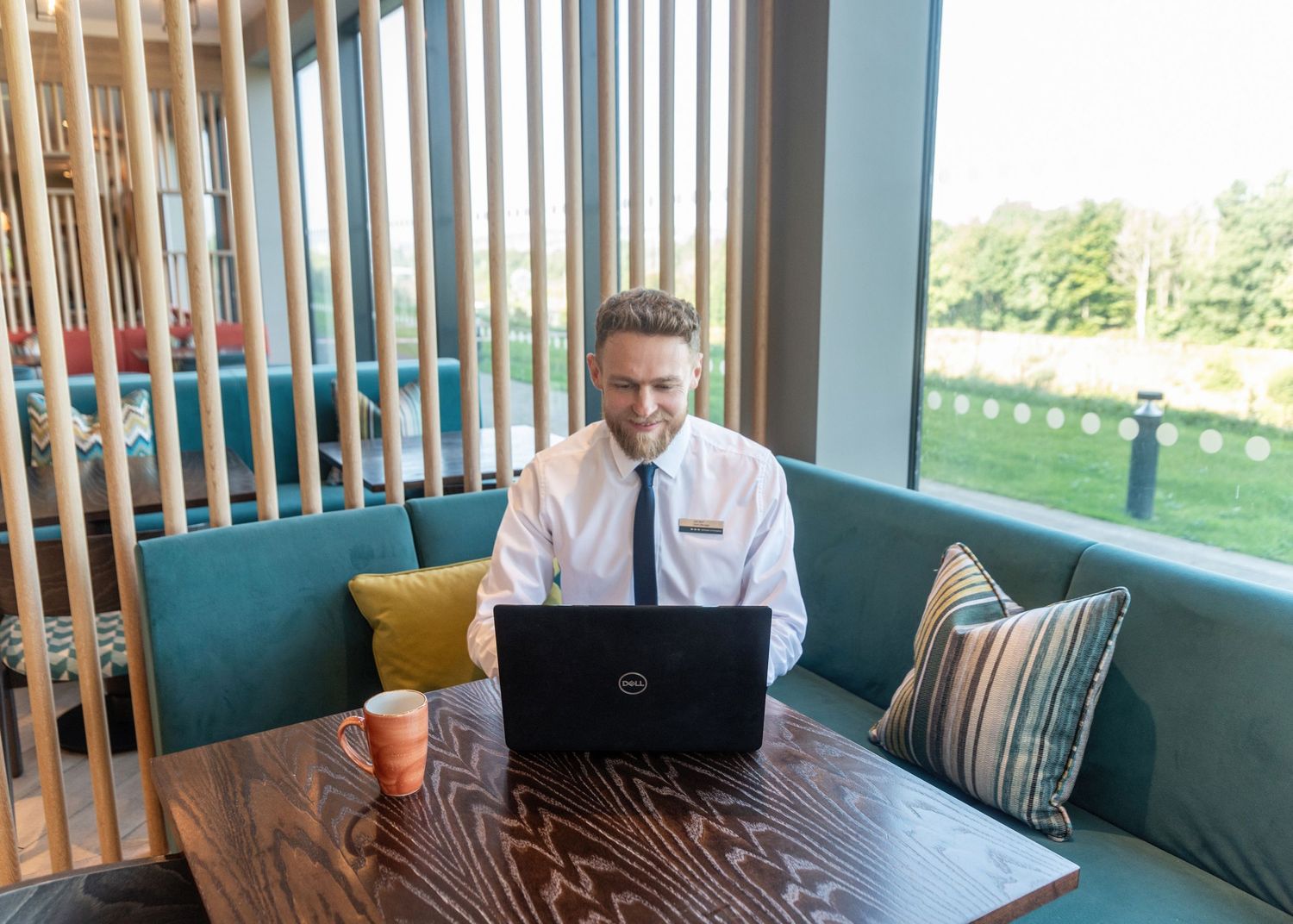 Modern workspace setup with laptop on wooden table against bright window view.