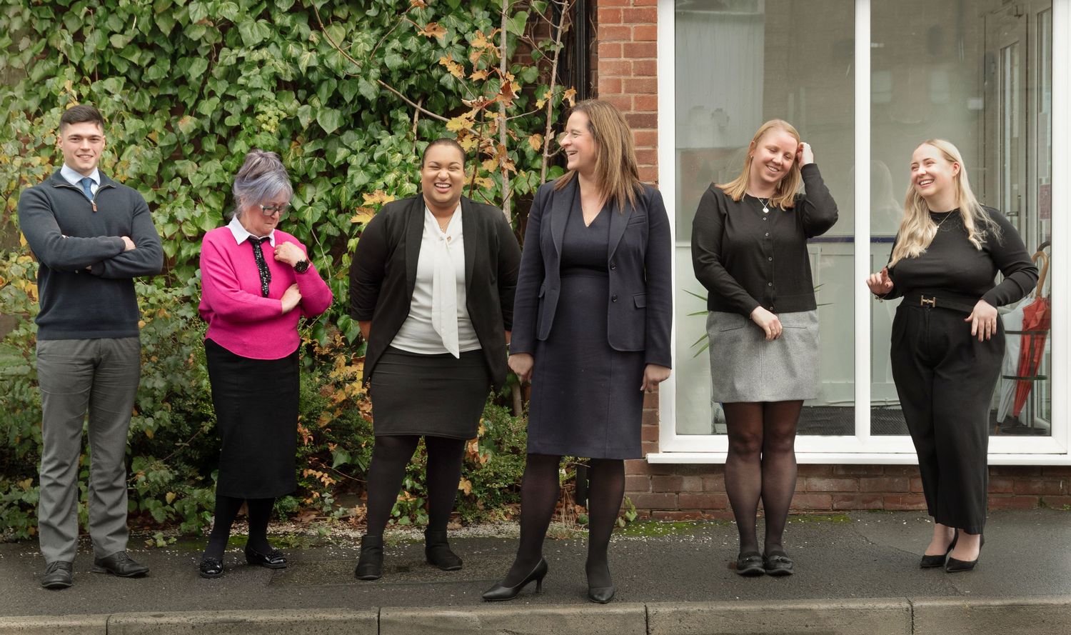 A group of professionals in business attire stand outside the Ellen Fay Solicitors office entrance.