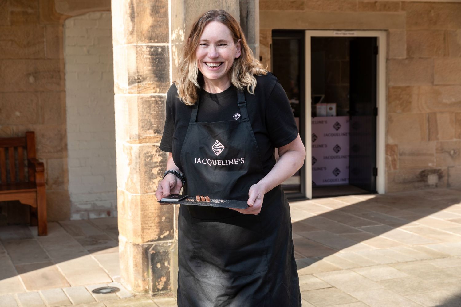 Staff member wearing black apron serves customers at Jacqueline's.