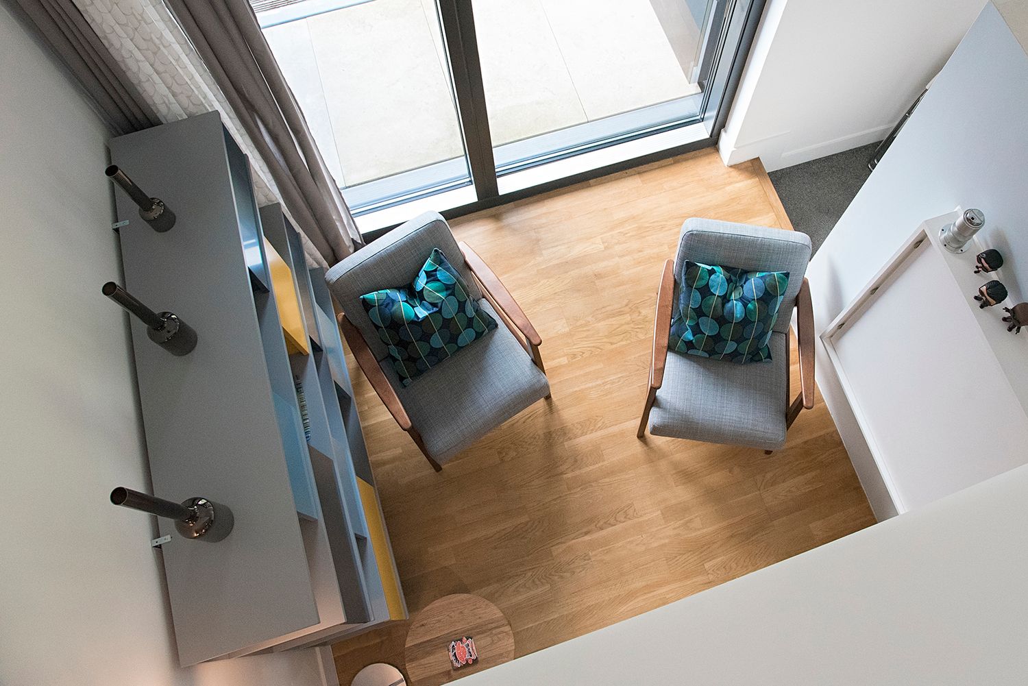 A bright modern bathroom with wooden flooring features a wall-mounted toilet and skylight window.