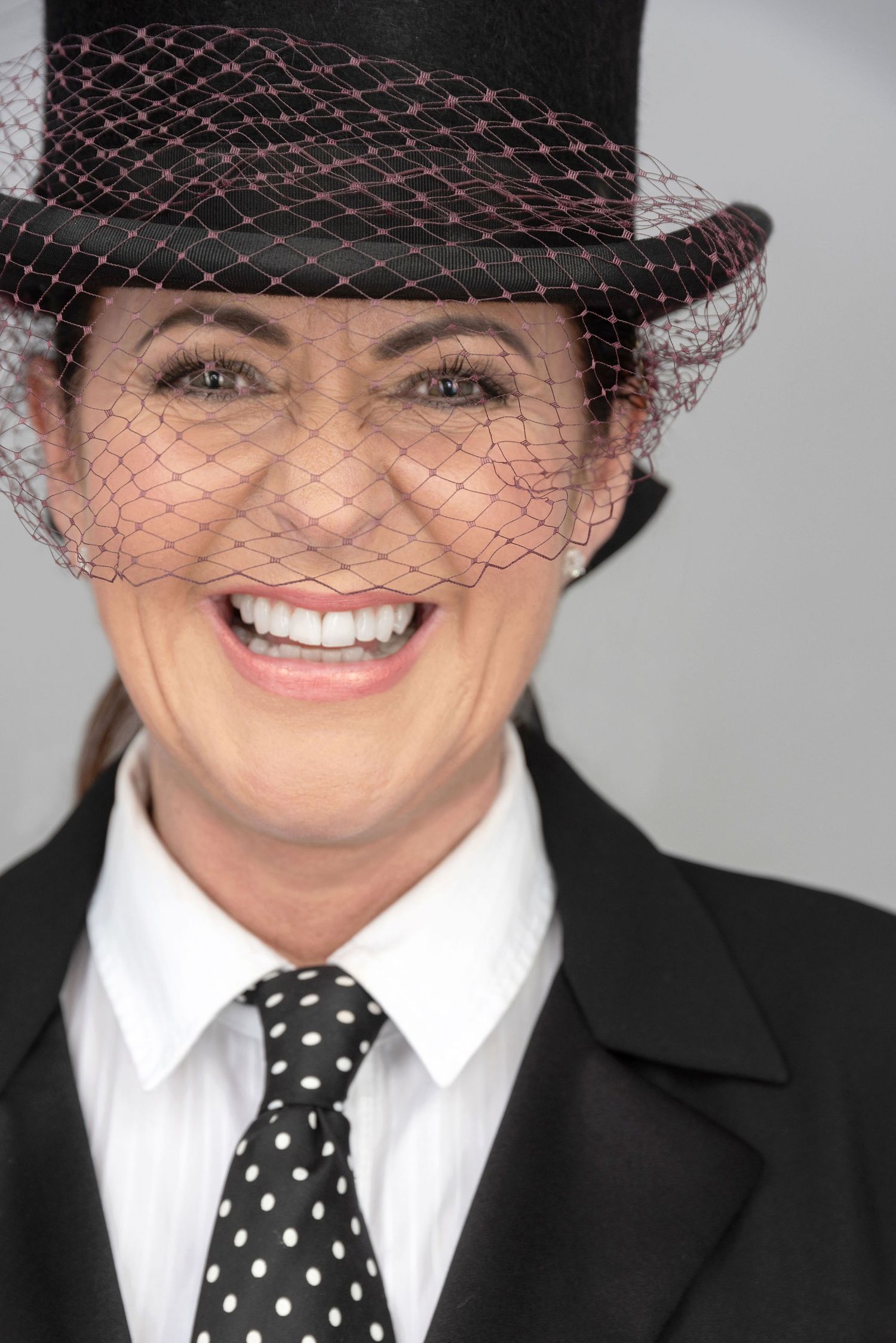 Professional headshot featuring top hat with veil and classic black and white formal wear.