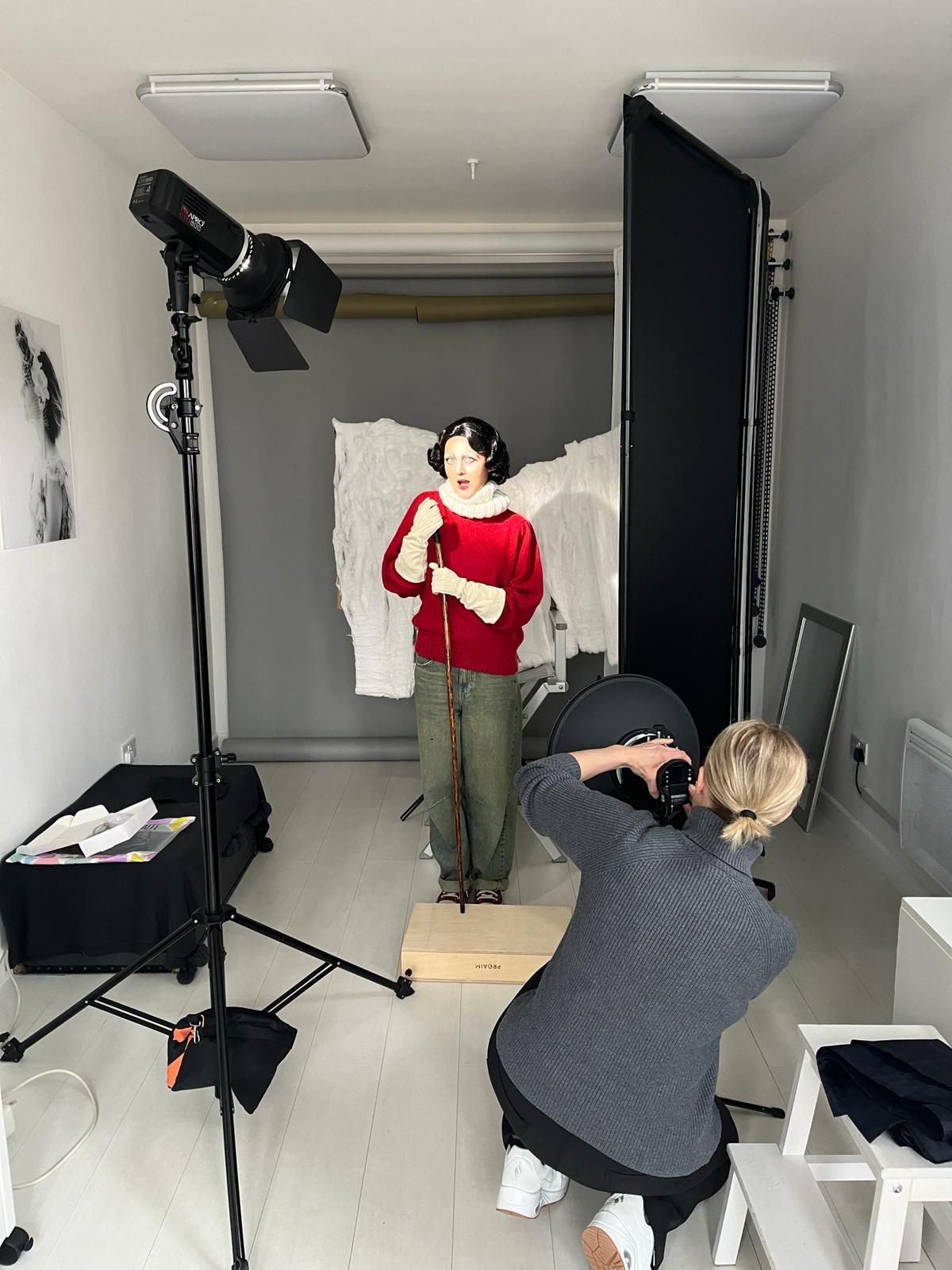 Wide shot of photography studio setup with lighting equipment and white backdrop.