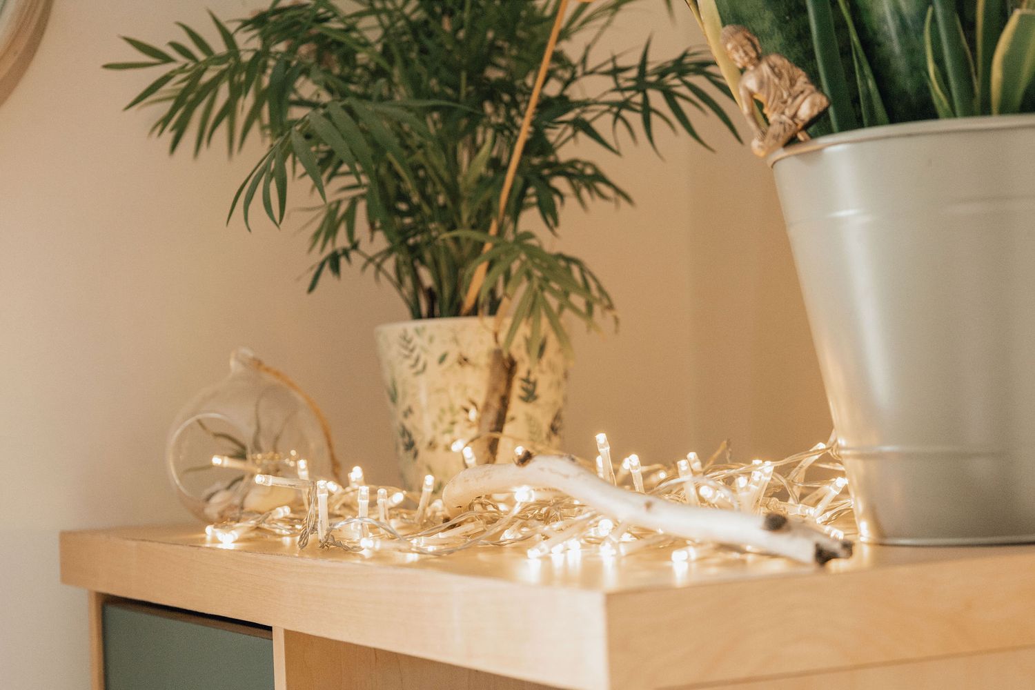 String lights and potted plants create cozy ambiance on wooden furniture.