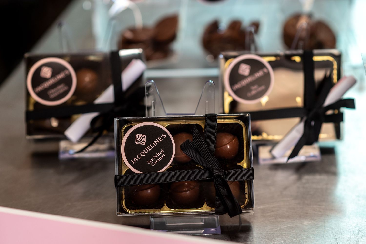 Rows of packaged chocolate boxes with black and gold branding displayed on a counter.