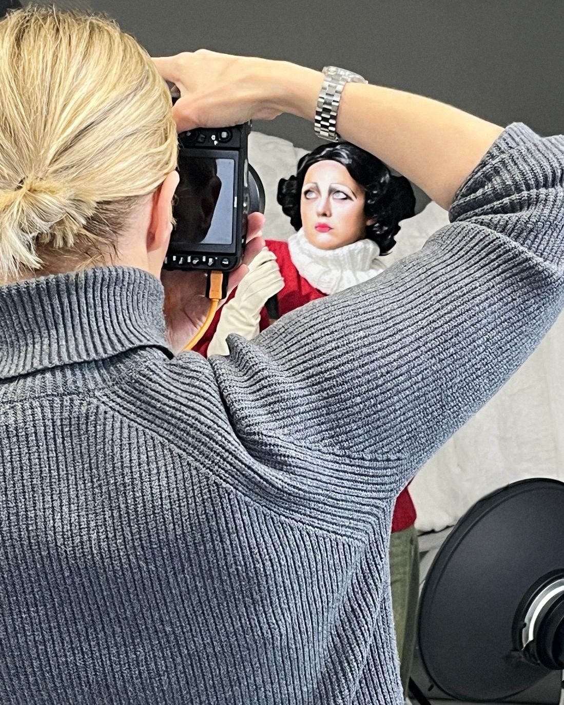 Photographer taking close-up shots of a vintage-inspired fashion scene in studio setting.