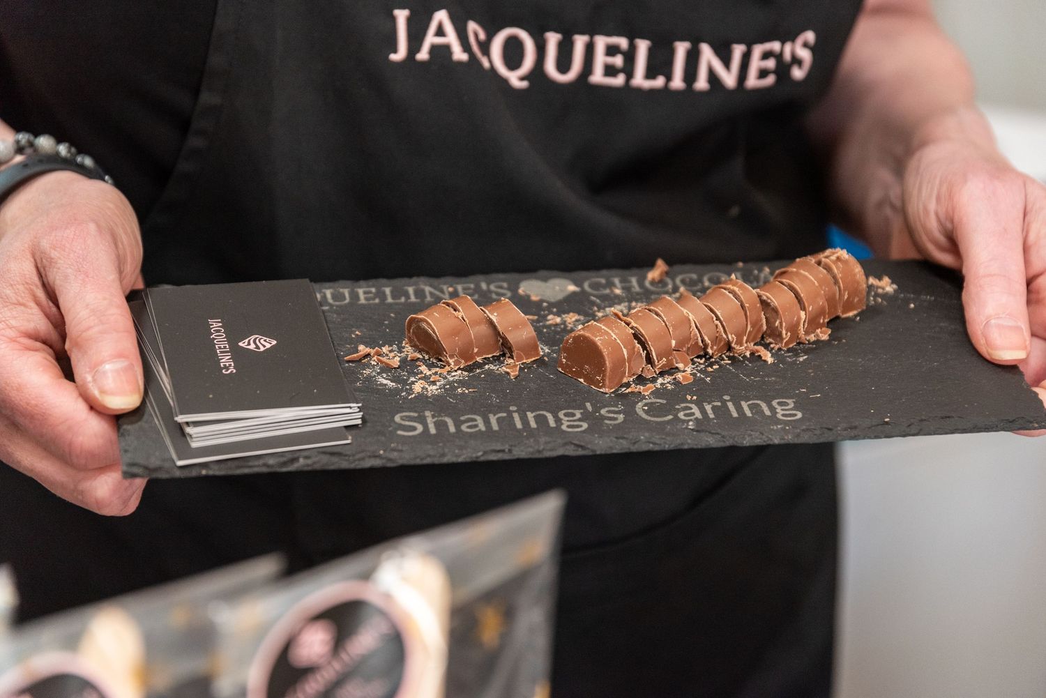 Row of chocolate truffles displayed on elegant black serving board.