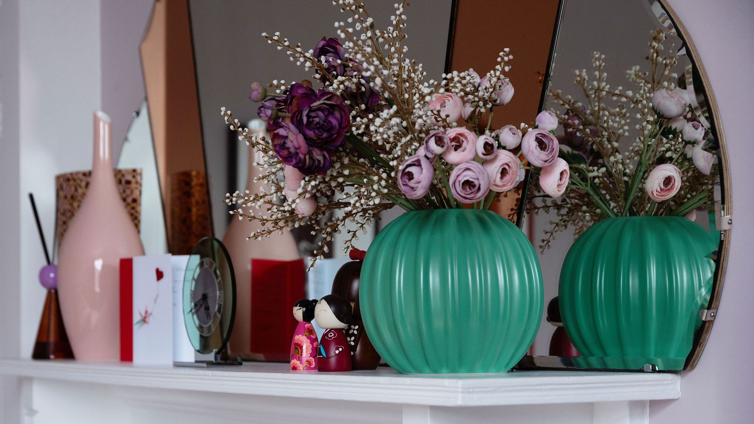 Decorative shelf display with turquoise glass vases, pink flowers, and white baby's breath arrangements.
