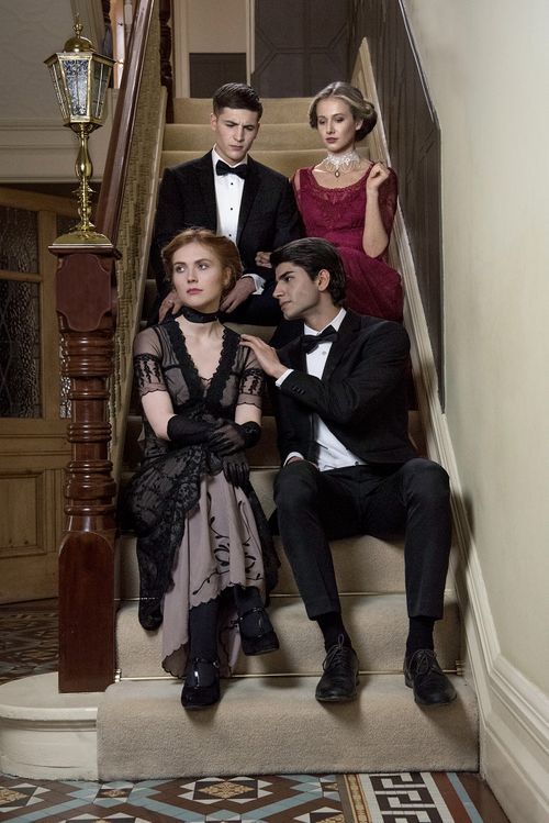 Four elegantly dressed young adults pose on a grand staircase in formal attire, including tuxedos and evening gowns.