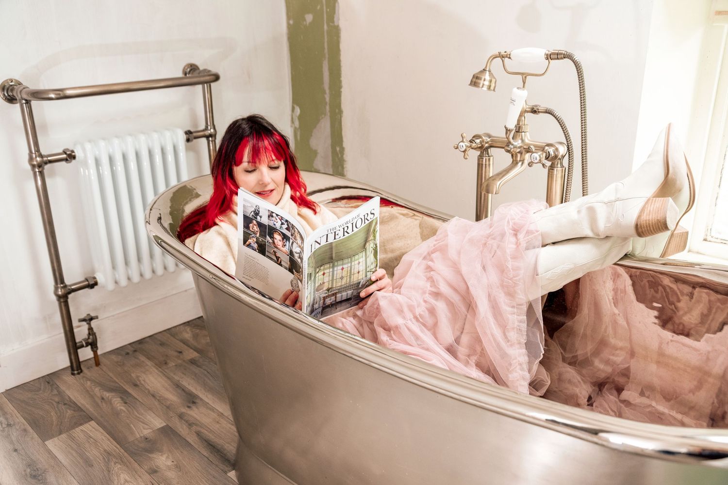 A serene bathroom interior with a freestanding tub, vintage-style fixtures, and soft pink accents.