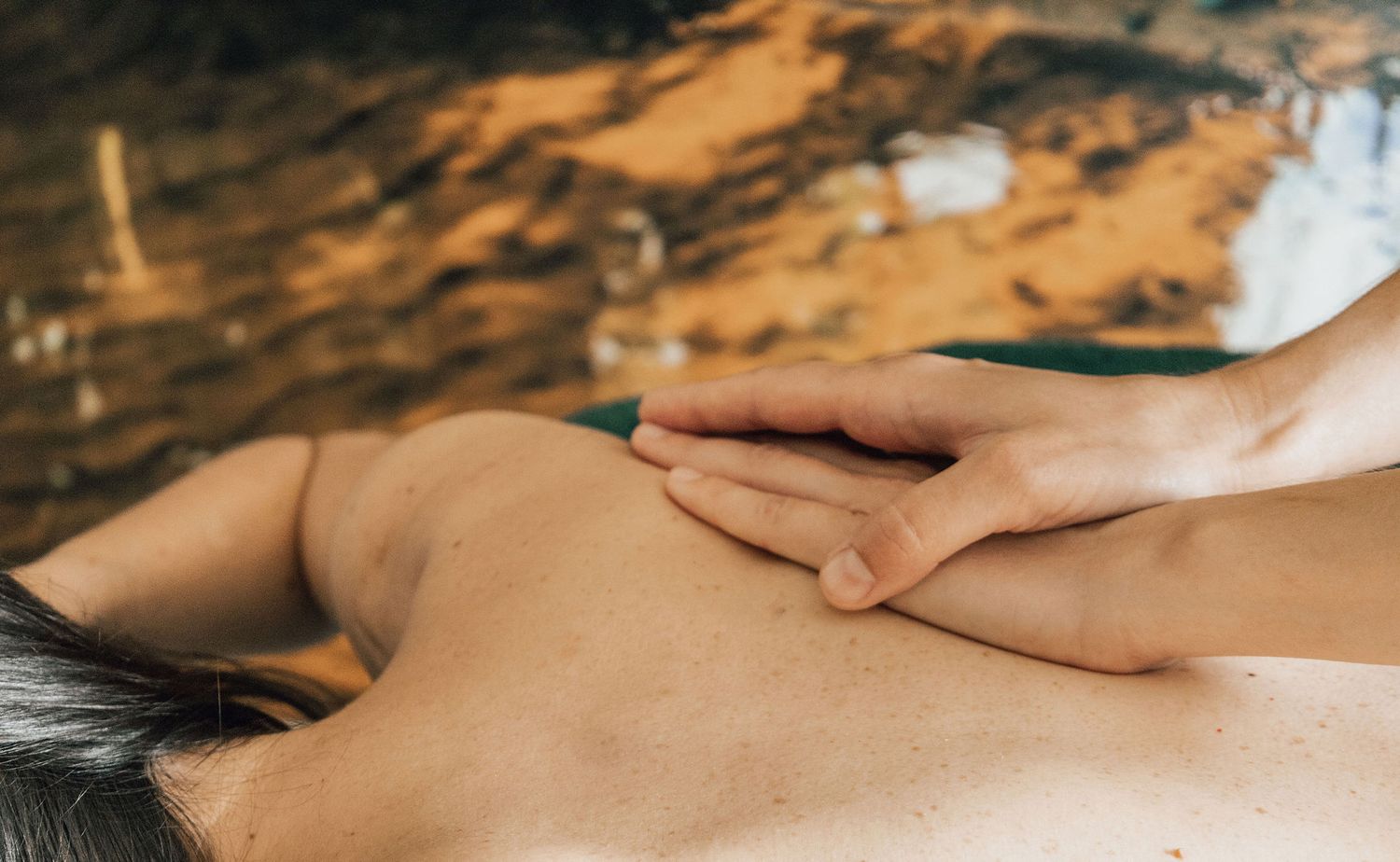 Close-up of hands performing therapeutic massage treatment on back muscles.