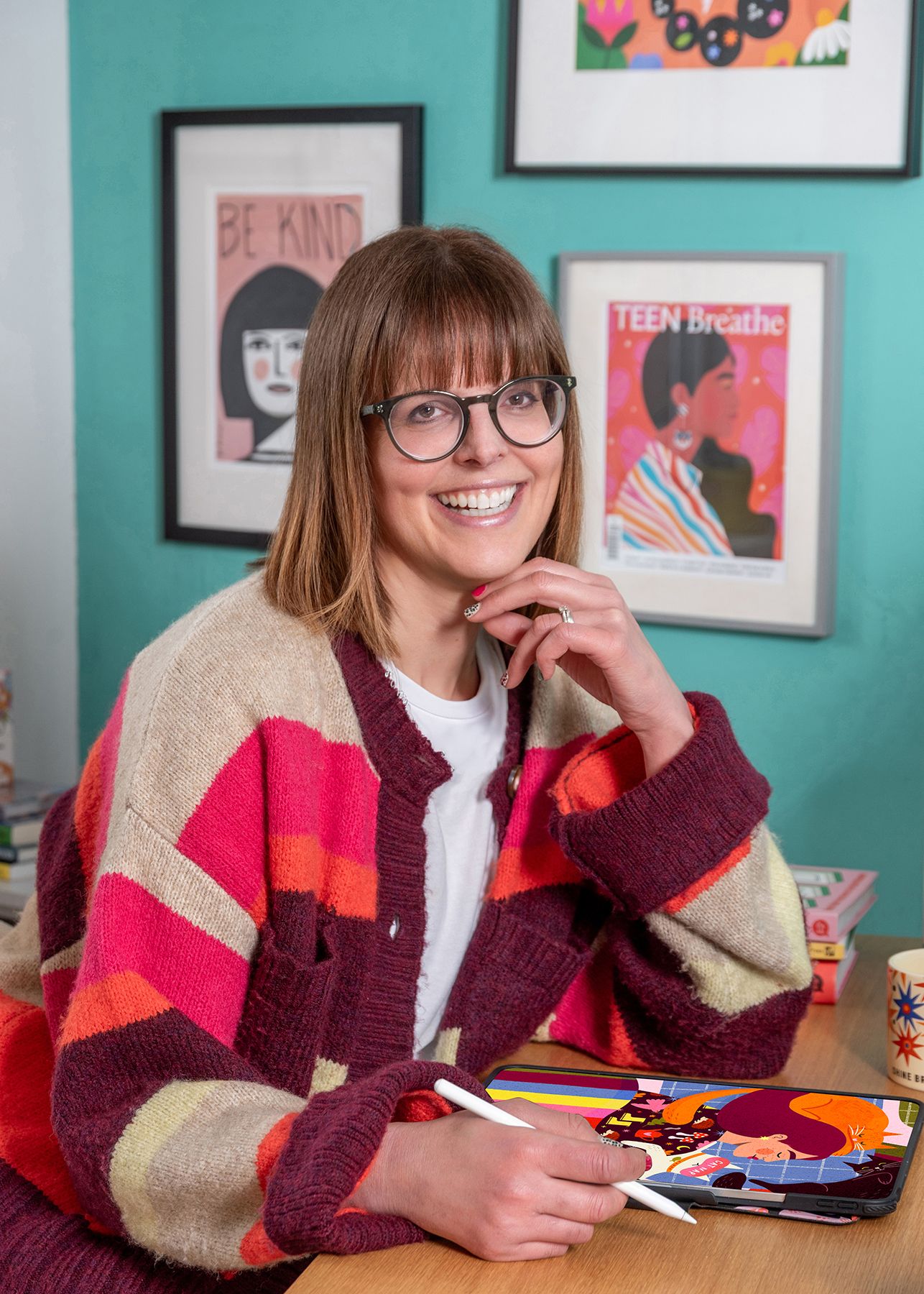 A colorful striped cardigan sweater is shown in multiple photos against a wall decorated with framed artwork.