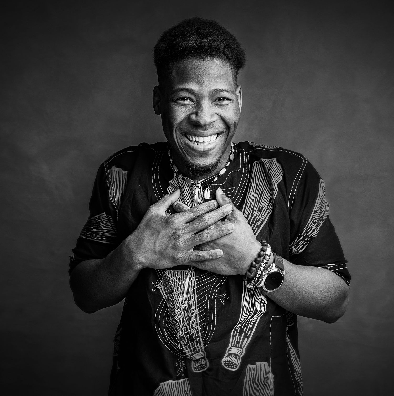 Portrait of a joyful person wearing a patterned traditional African shirt in black and white.