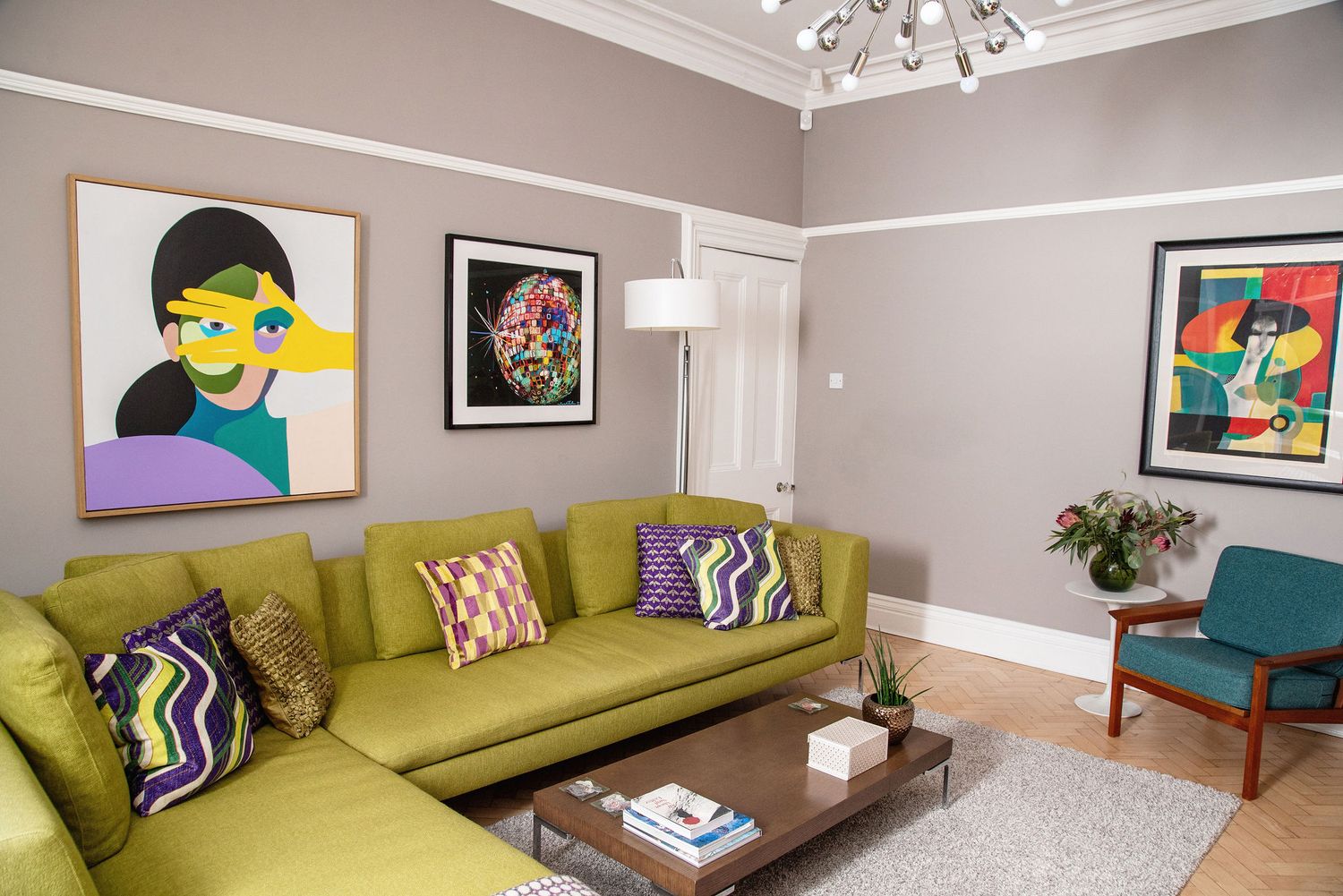 Modern living room with chartreuse sofa, pop art on gray walls, and teal accent chair features colorful throw pillows.