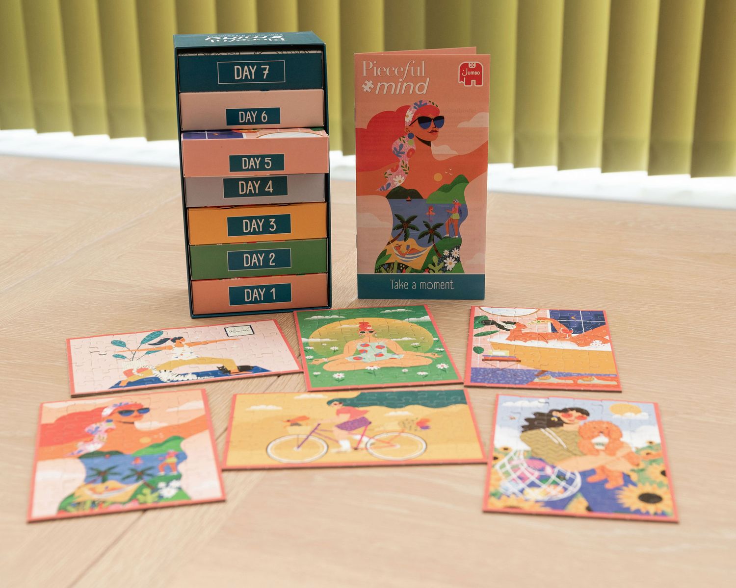 Colorful children's books displayed in a row on a beige surface with vertical blinds in the background.