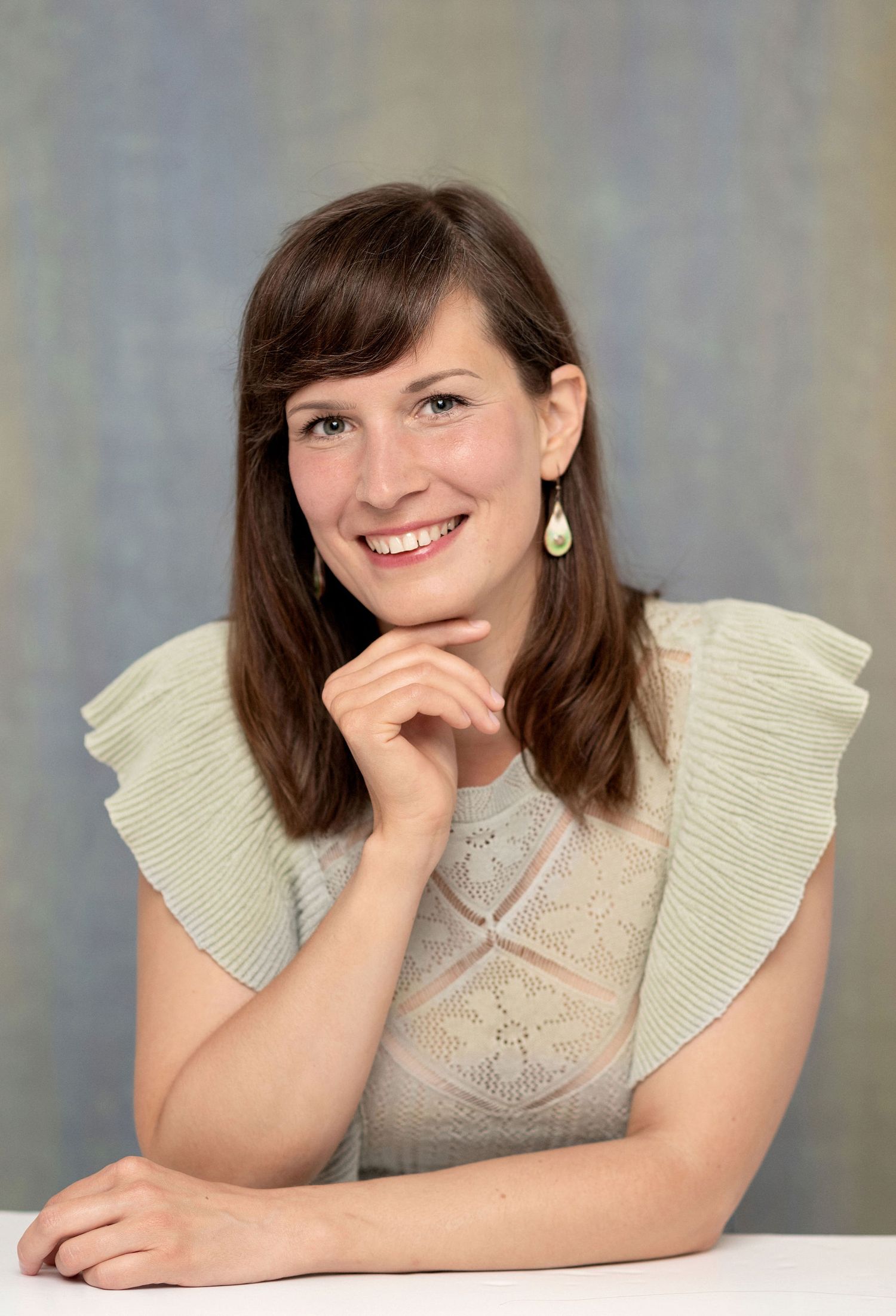 Studio portrait featuring cream knit top with ruffled shoulders and soft lighting.