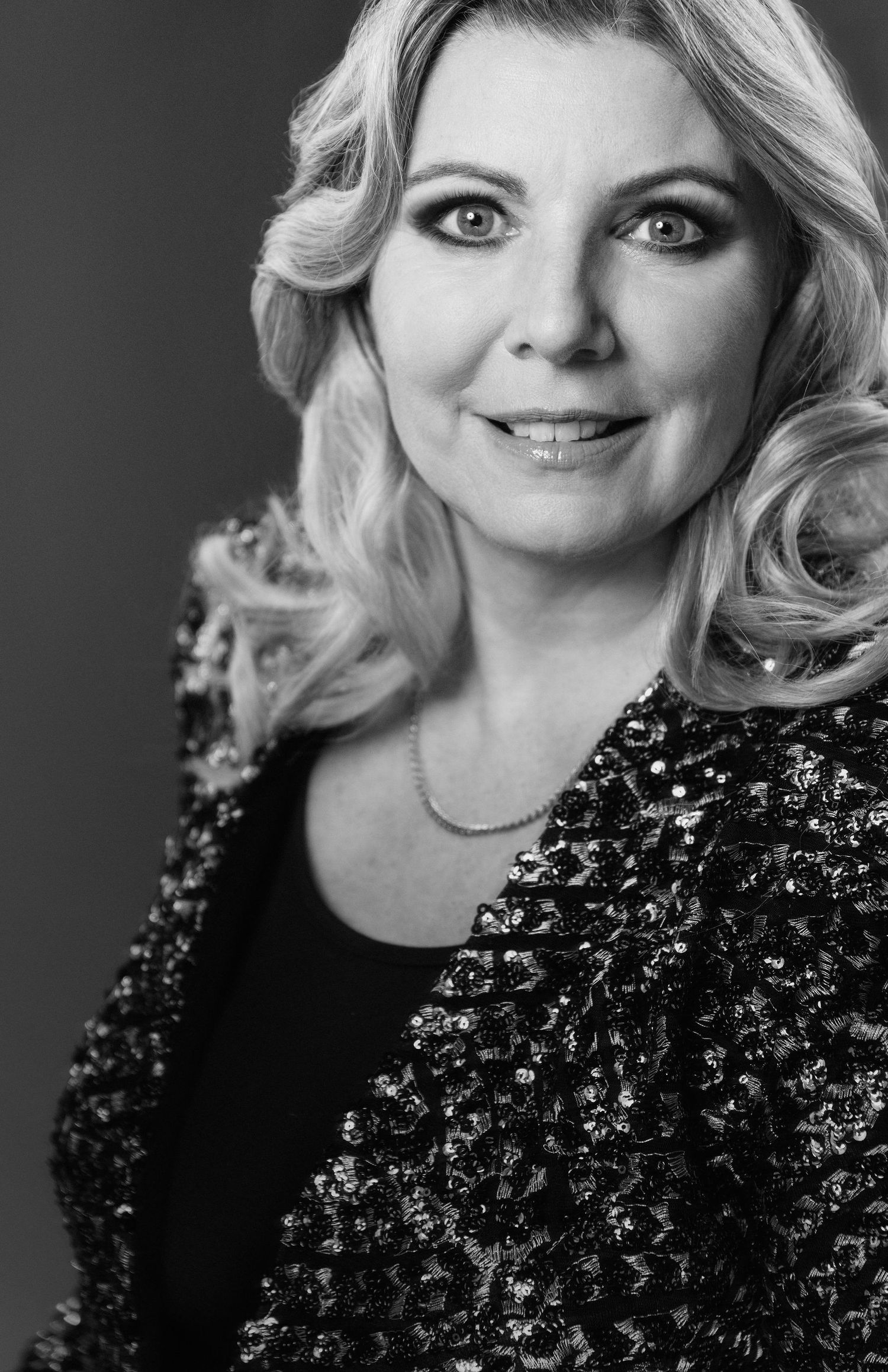Classic black and white portrait showing elegant makeup and a sequined jacket.