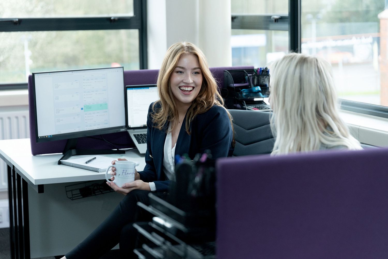 People working together in a modern office space with computers and desks in an open collaborative environment.