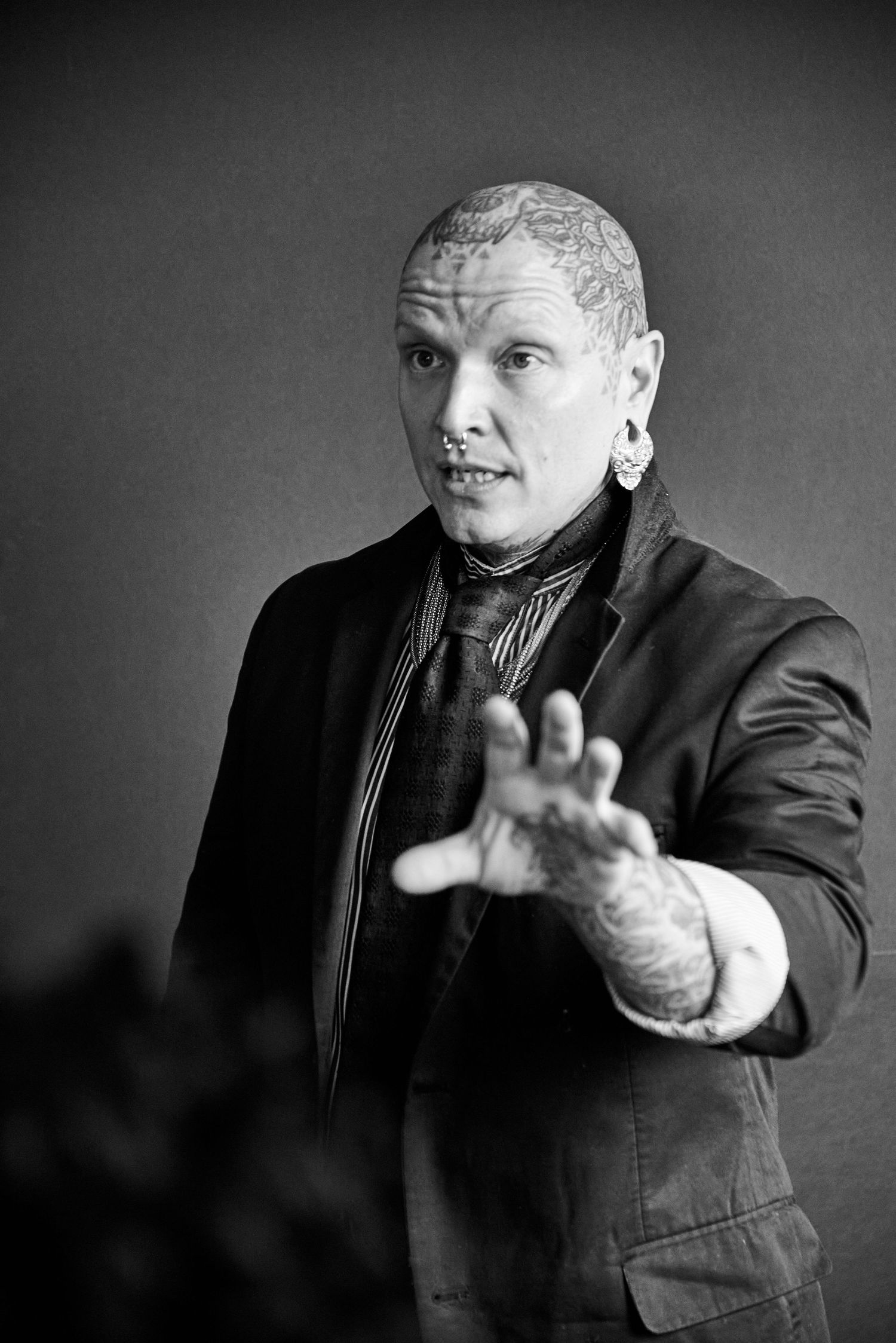 Dramatic black and white portrait of performer making expressive hand gesture.