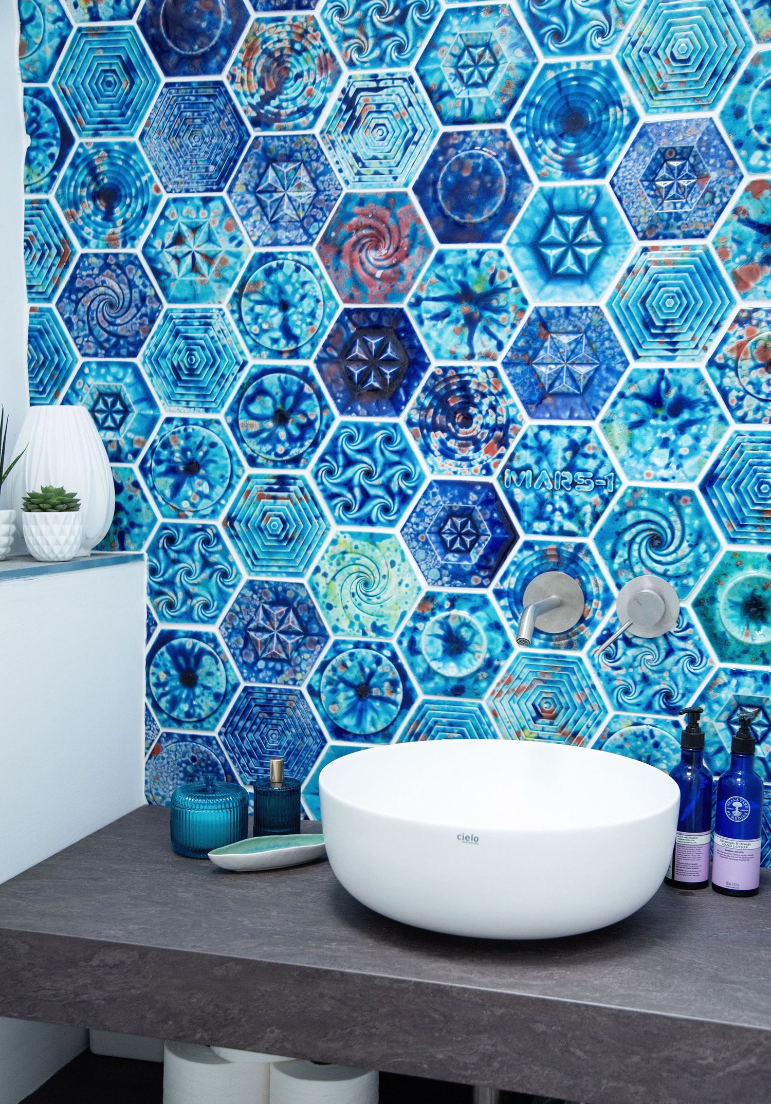 Modern bathroom design featuring vibrant blue hexagonal mosaic tiles with intricate patterns and a white vessel sink.