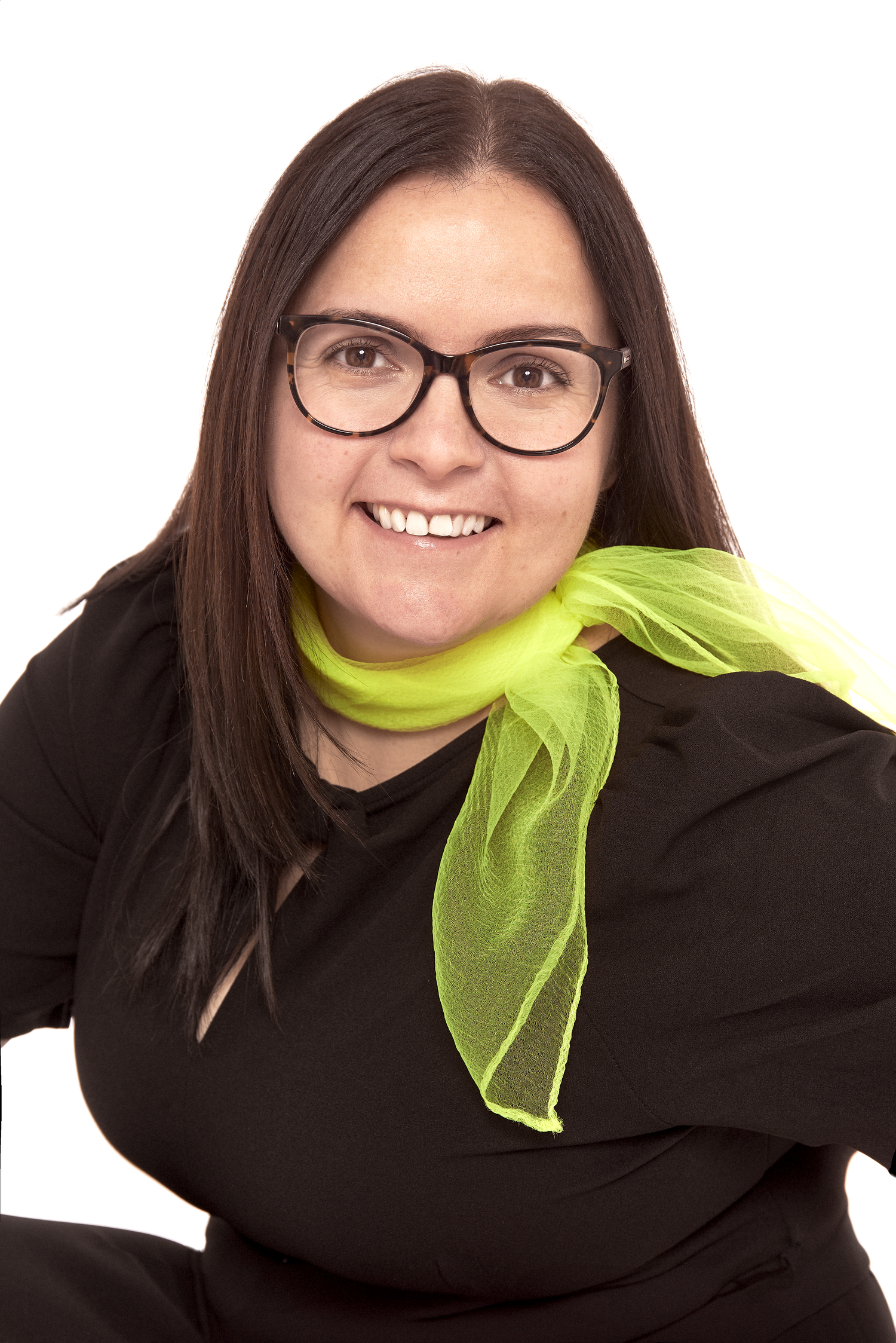 Portrait wearing a black sweater and bright lime green scarf with glasses against white background.