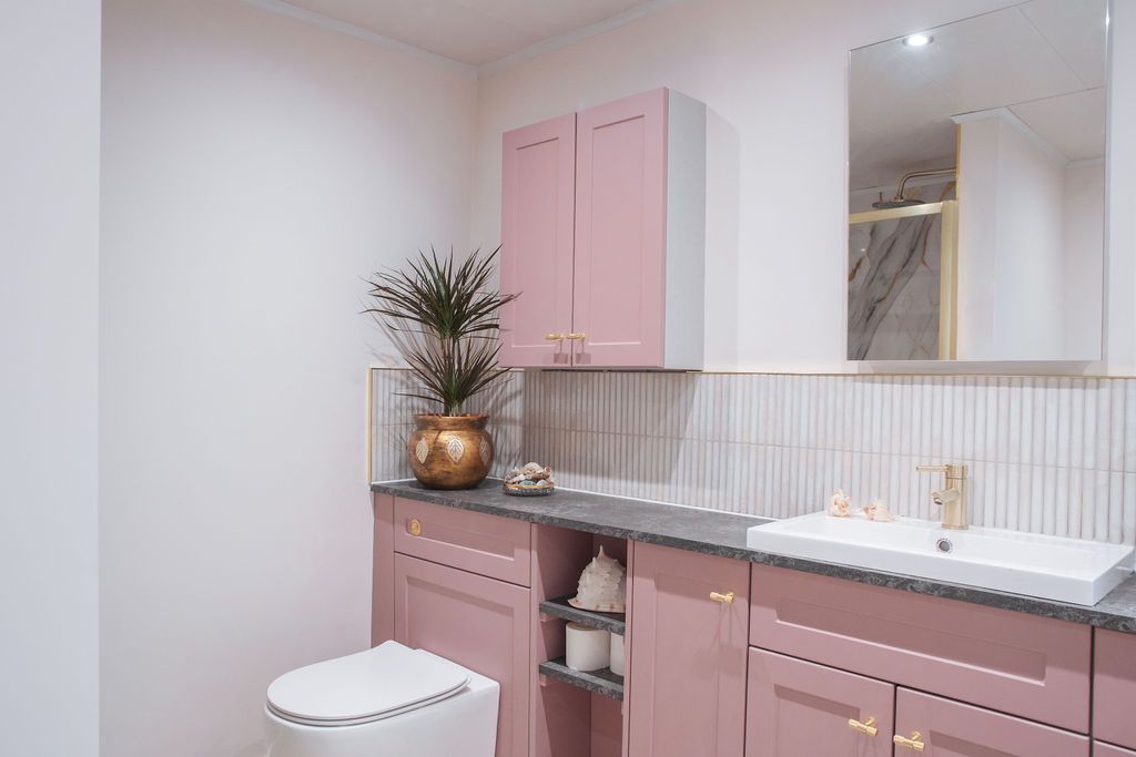 Modern pink and white kitchen interior with sleek cabinetry, white countertops, and minimalist design features.