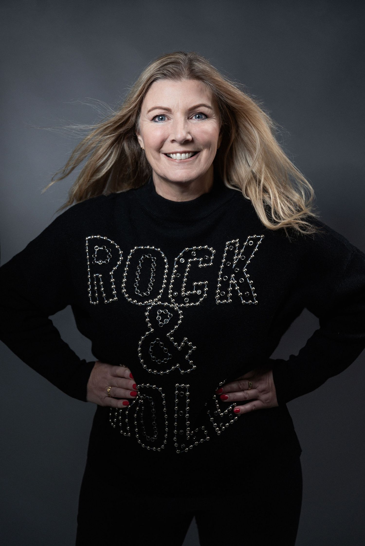 A black sweater with rhinestone 'ROCK & ROLL' lettering photographed against a dark background.