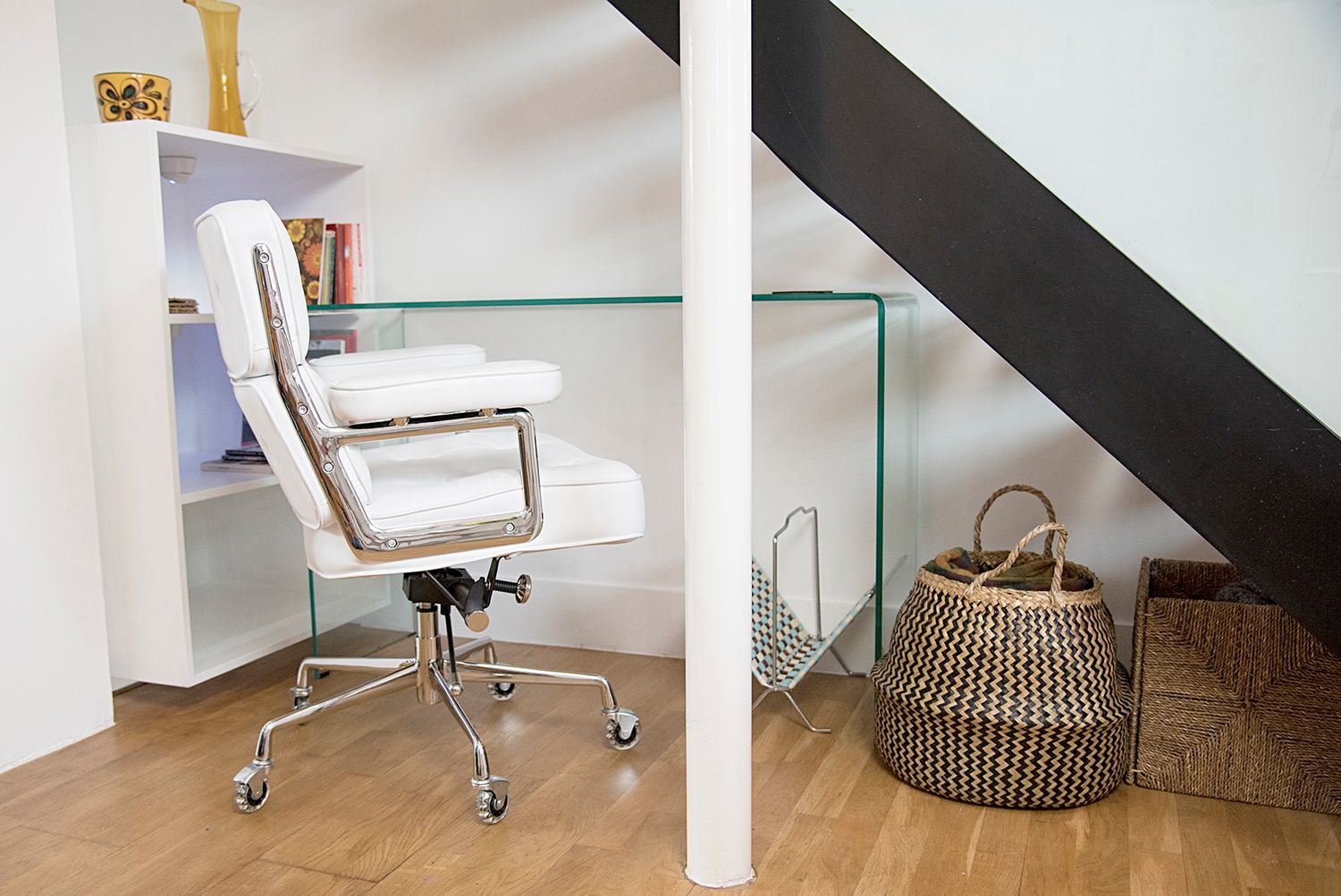 Minimalist home office setup with white furniture and sloped ceiling in a bright modern attic space.