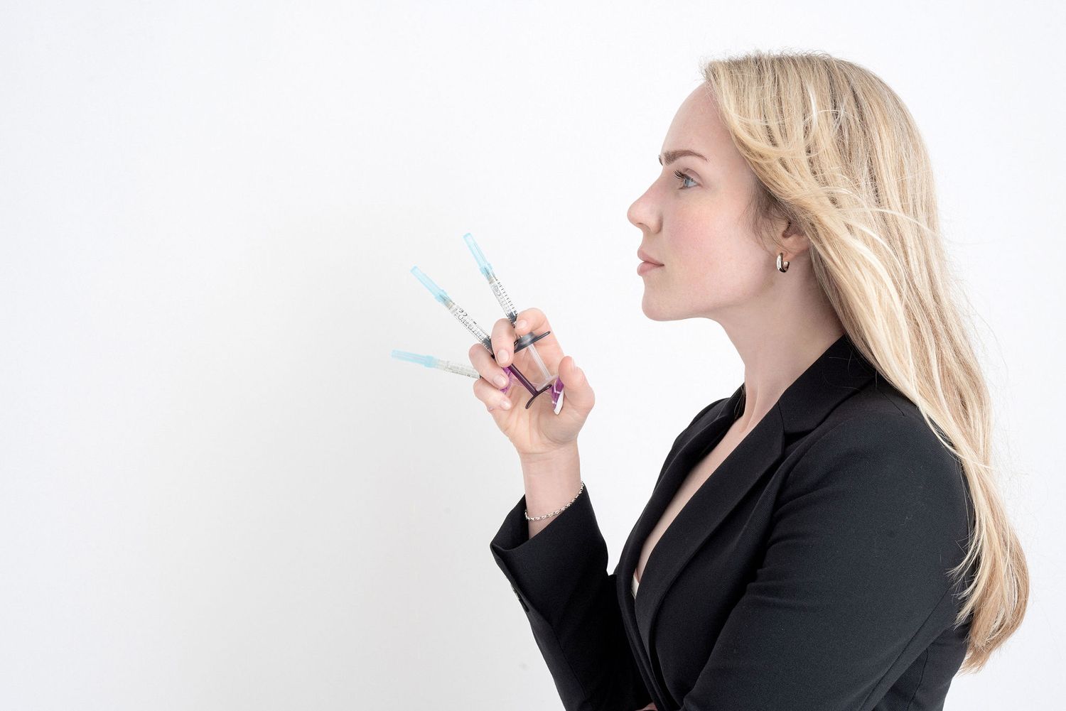 Professional in business attire examining acupuncture needles.
